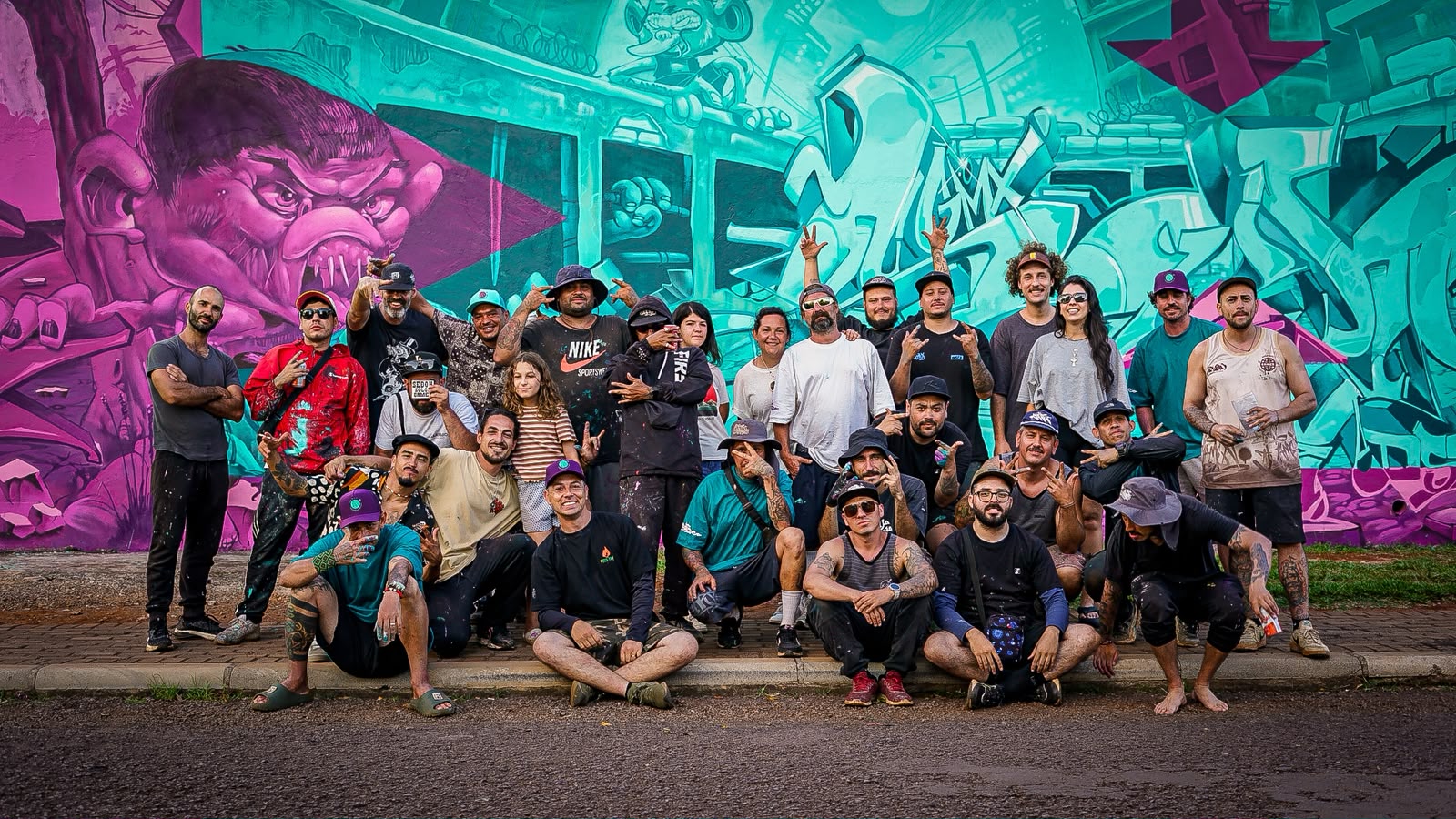 Artistas de GAMEX reunidos frente a un mural morado y celeste