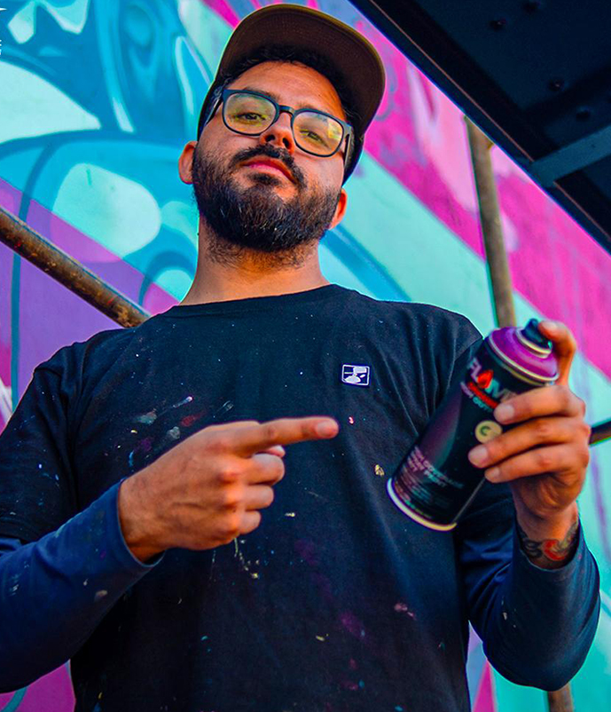 Patricio Tormento con un aerosol frente a un mural